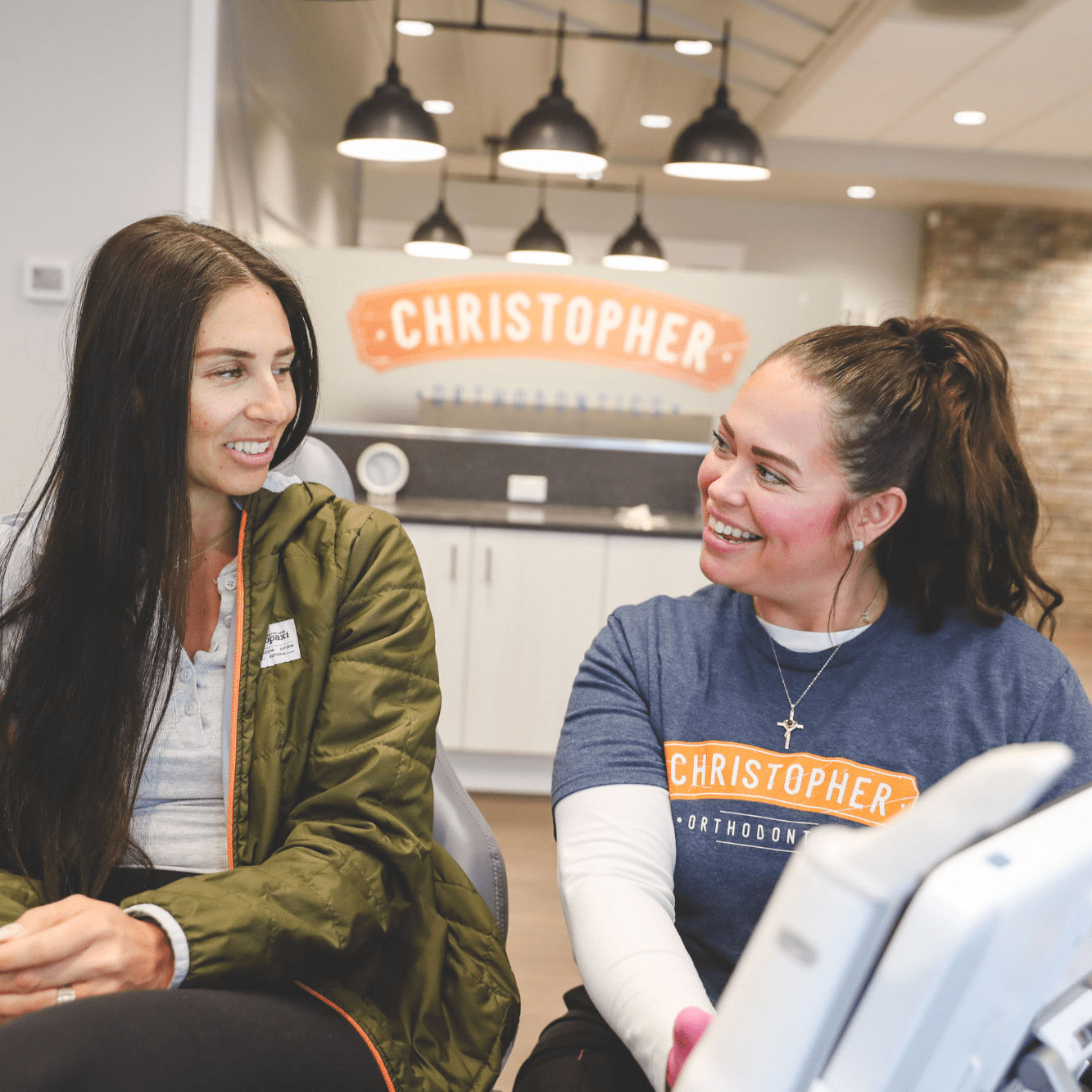 Two women smiling and talking in the Christopher Orthodontics office